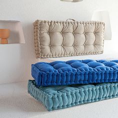 two blue and beige pillows sitting next to each other in front of a white wall