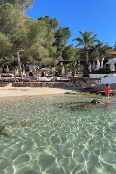 a person standing in shallow water near the beach