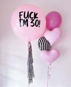 pink balloons with black and white tassels are hanging from the wall, saying i'm 50