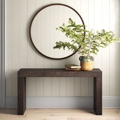 a wooden table with a potted plant on it and a round mirror above it