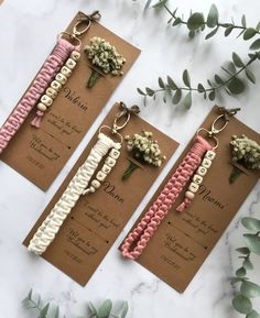 three wedding favors with flowers on them are laid out next to some leaves and greenery