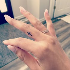 a person's hand with a small cross tattoo on it, and a ring