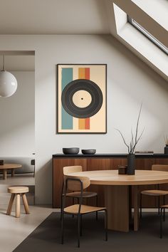 a dining room table with chairs and a painting on the wall above it, in front of a window