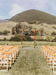 an outdoor ceremony set up with wooden chairs