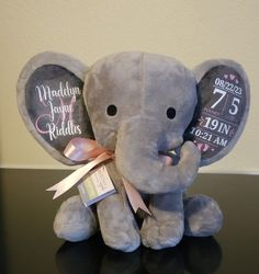 an elephant stuffed animal with a pink ribbon around its neck sitting on a black table