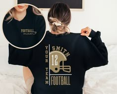 a woman wearing a black football sweatshirt with the number 12 on it and her hair in a pony tail