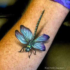 a blue dragonfly tattoo on the wrist