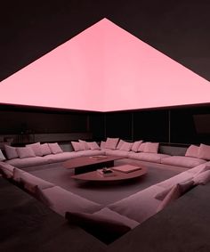 a large couch sitting under a pink light