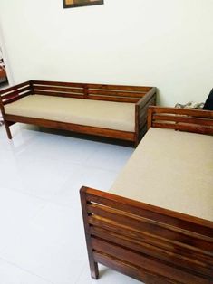 two wooden couches sitting next to each other in a living room with white tile flooring