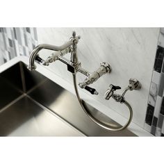 a stainless steel sink with two faucets on the wall and tiled backsplash