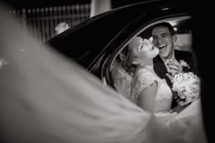 a bride and groom kissing in the back seat of a car at their wedding reception