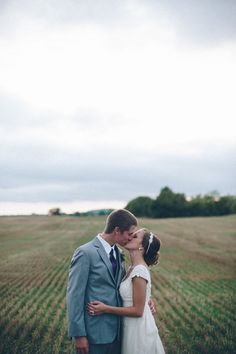 a bride and groom kissing in the middle of an open field on their wedding day