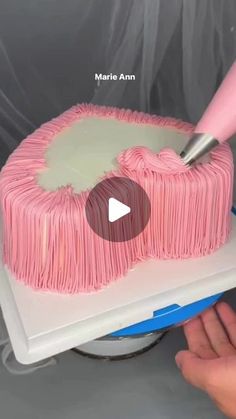 someone is decorating a cake with pink icing