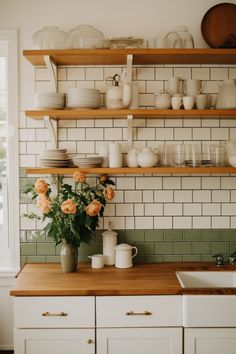 the kitchen counter is covered with dishes and flowers in vases, cups, and bowls