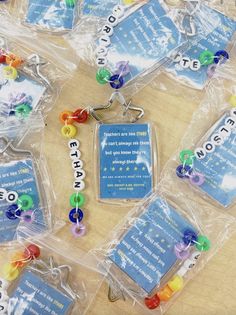 many different colored beads in plastic bags on a wooden table with words written on them