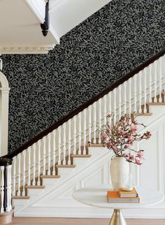 a vase filled with flowers sitting on top of a table next to a stair case