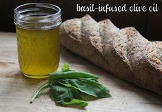 bread and olive oil on a cutting board with basil leaves next to it, in front of a loaf of bread