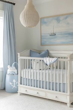 a baby's room with a white crib, blue curtains and a painting on the wall