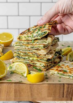 a person holding a piece of flatbread on top of a cutting board with lemons