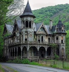 an old abandoned house in the middle of a wooded area with mountains in the background