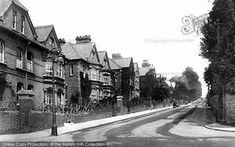 an old black and white photo of a street in the early 20th century, with houses on both sides