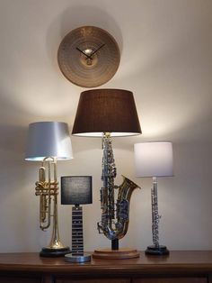 a lamp and some musical instruments sitting on a table with a clock above it that is mounted to the wall