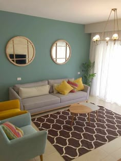 a living room filled with furniture and two round mirrors on the wall above it's windows