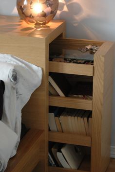 a lamp is sitting on top of a wooden table next to a book shelf with books