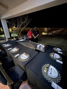 two men standing next to each other at a table with plates and silverware on it