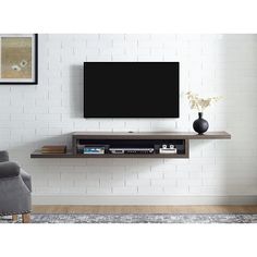 a flat screen tv sitting on top of a wooden shelf next to a gray chair