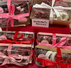 several boxes filled with different types of cookies and candies in pink ribbon tied around them