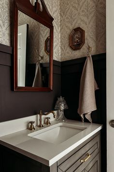 a bathroom sink sitting under a mirror next to a wall mounted faucet in front of a wooden framed mirror