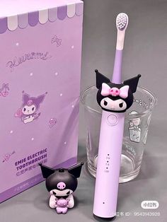 an electric toothbrush next to a purple box with a cat figurine on it