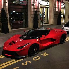 two red sports cars parked on the street in front of a building at night time