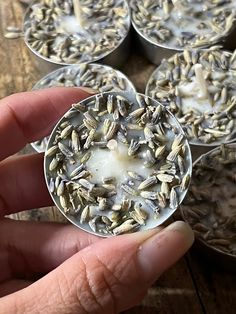 a person holding an object in their hand near some tins with seeds on them