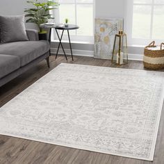 a living room with a gray couch and white rugs on the hardwood flooring