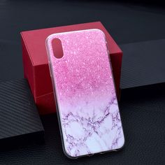 a pink and white marble phone case sitting on top of a red box next to a black surface