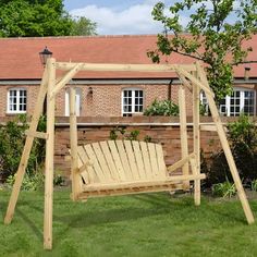 a wooden swing in the grass near a brick building