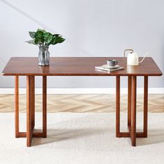 a wooden table with two vases on it and a book next to the table