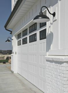 a white garage door with a black light on it's side next to a house