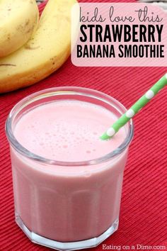 a pink smoothie in a glass with a green straw next to bananas on a red cloth