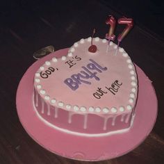 a pink birthday cake with candles on top