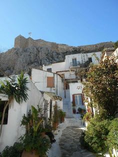 an alley way with steps leading up to some buildings and mountains in the background on a sunny day