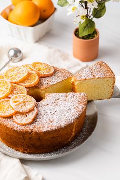 a cake on a plate with slices cut out and some flowers in the back ground