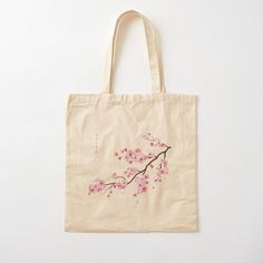 a tote bag with pink flowers painted on the front and side, hanging from a white wall