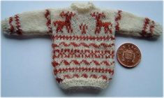 a red and white knitted sweater next to a penny