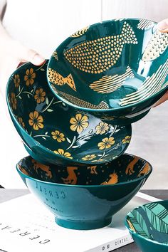 three bowls are stacked on top of each other with fish painted on them and flowers