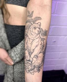 a woman's arm with a bear and flowers tattoo on the left side of her arm