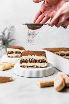 someone sprinkling sugar on top of a piece of cake that is sitting on a plate