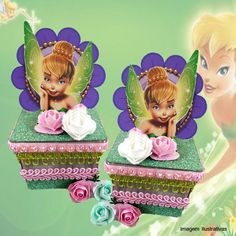 two little tinkerbells sitting on top of a green box with pink flowers